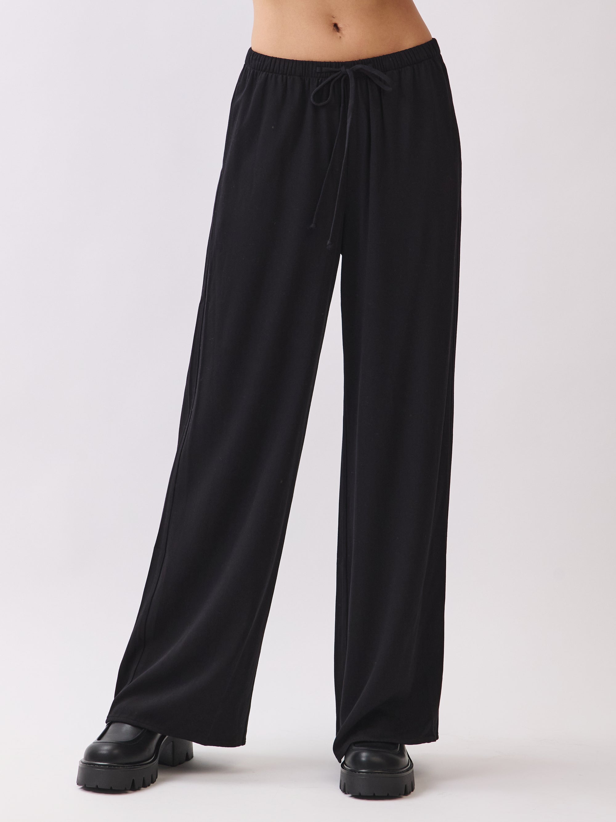 BTTRMMT black wide-leg drawstring pants shown with chunky black shoes, featuring a soft relaxed fit perfect for everyday wear