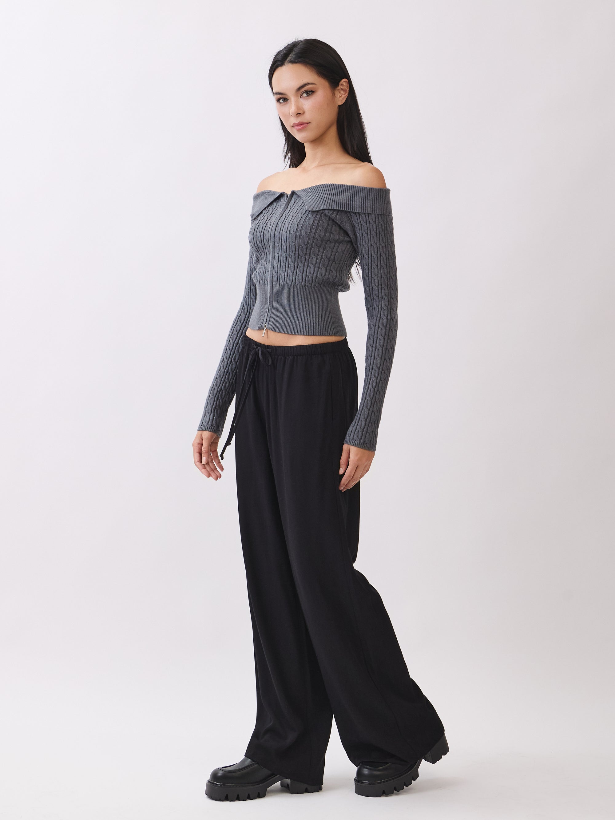 Side view of model wearing the BTTRMMT Camille Zip Knit in charcoal gray, showing the off-shoulder ribbed fit and cropped silhouette.