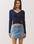 Model wearing BTTRMMT navy ribbed V-neck knit top paired with light wash denim mini skirt, studio front view.