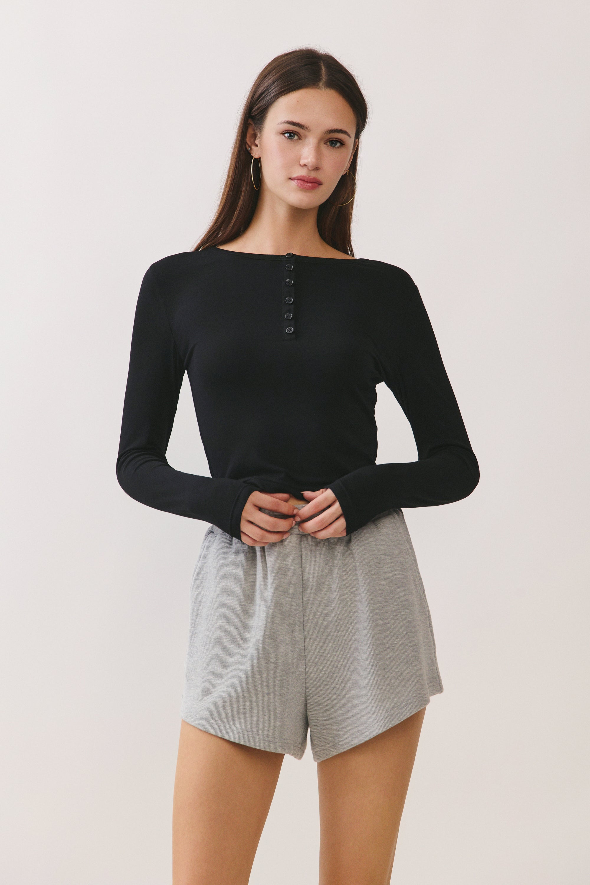 Model wearing BTTRMMT Black Aubree Henley Top with long sleeves, button neckline, and fitted silhouette.