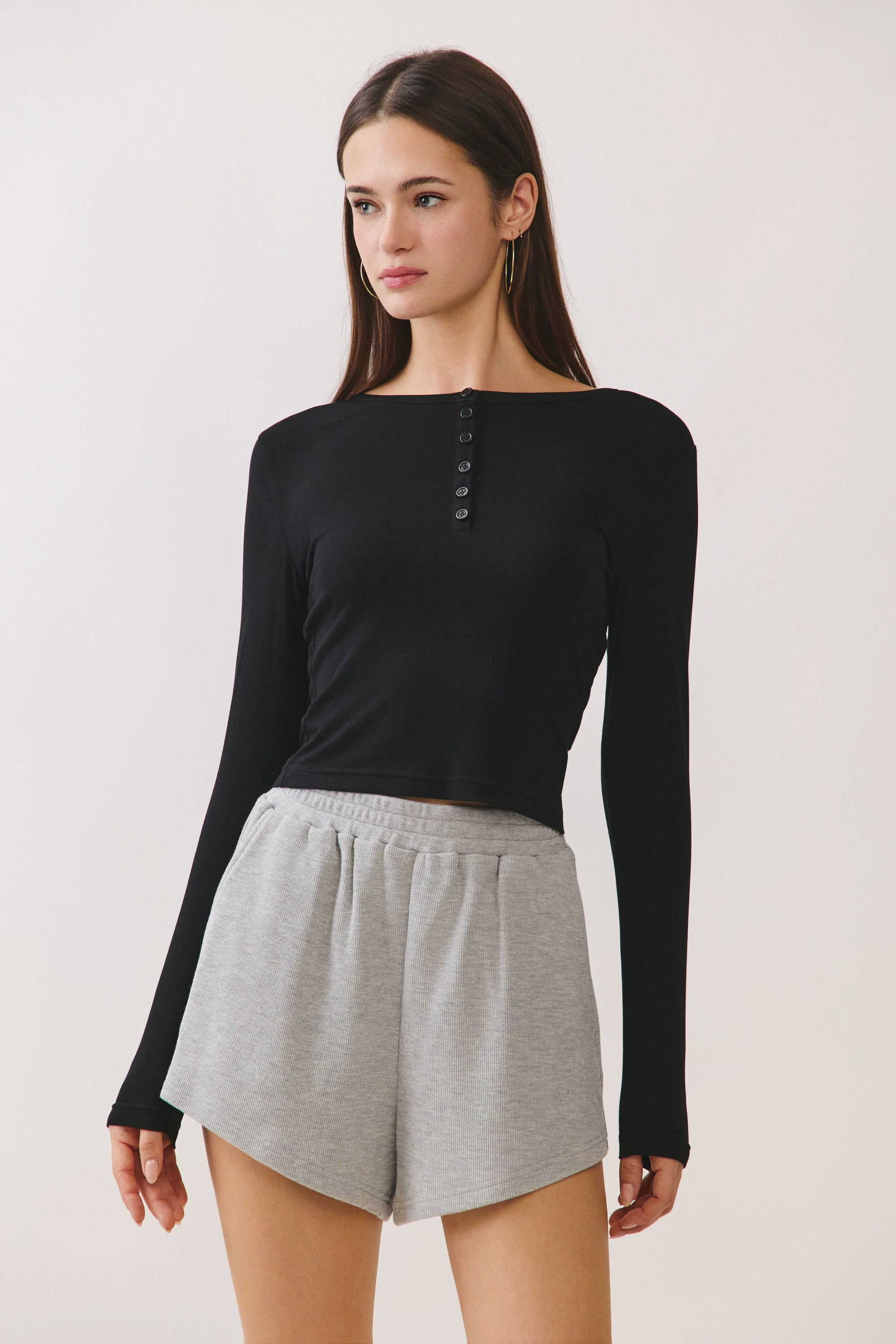 Model wearing BTTRMMT Black Aubree Henley Top with long sleeves, button neckline, and fitted silhouette.