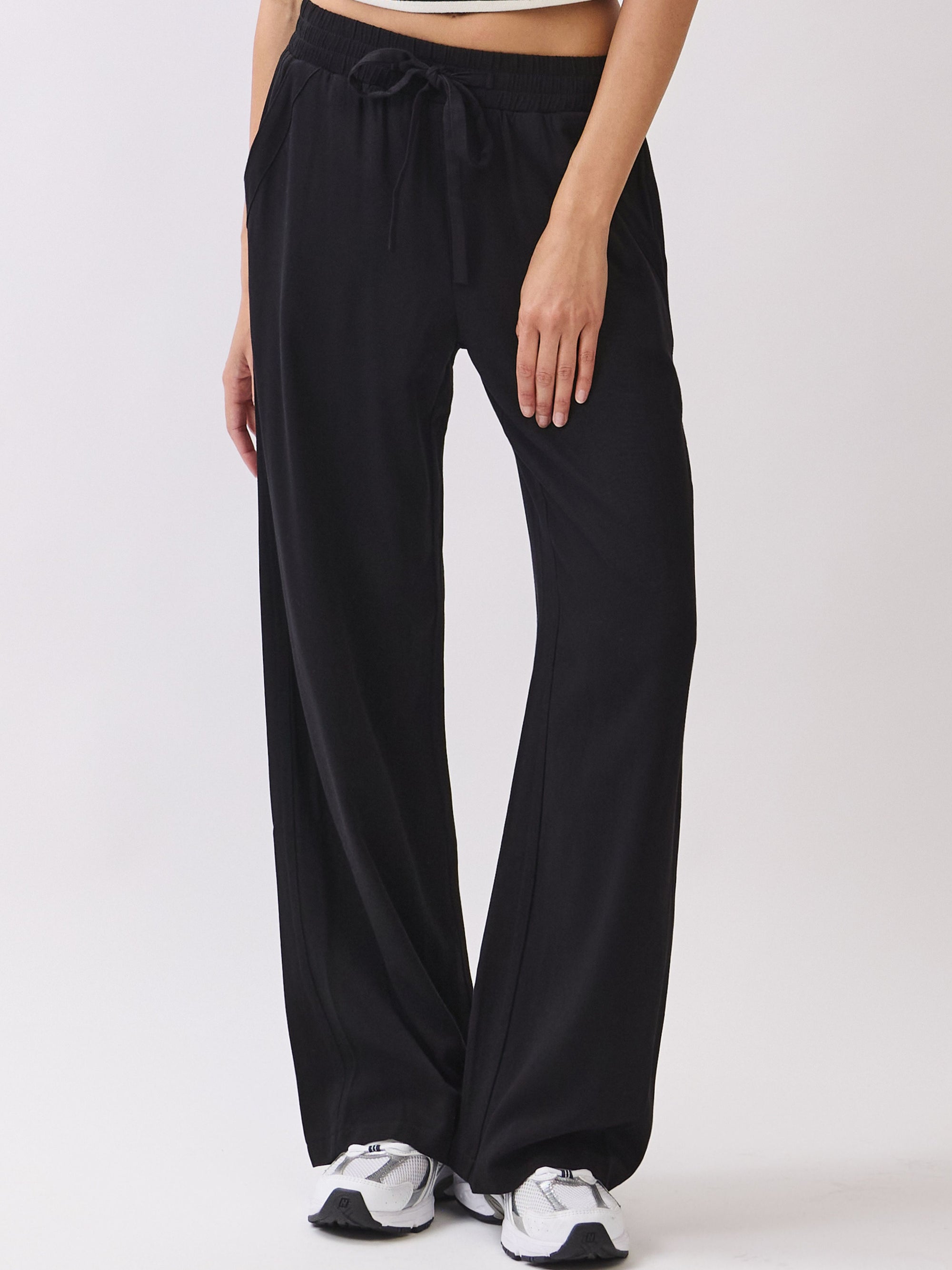 BTTRMMT Black Yuna Soft Wide Leg Pants front view with a drawstring waistband, relaxed drape, and casual fit styled with sneakers.