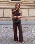 Model wearing the BTTRMMT Daniela Off-Duty Set in brown, featuring a one-shoulder ruched top and matching wide-leg pants for an elevated casual look.