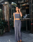 Model wearing BTTRMMT Denim Olivyn Set in blue, featuring cropped square-neck top and flowy wide-leg pants, standing outside a café.