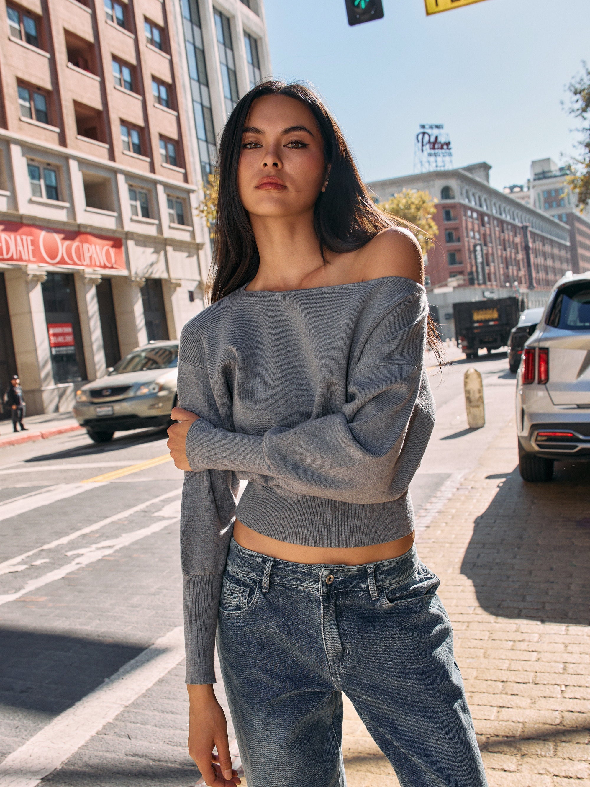 Model in BTTRMMT Gray Tessa Boatneck Sweater, off-shoulder knit styled with jeans in sunlight.
