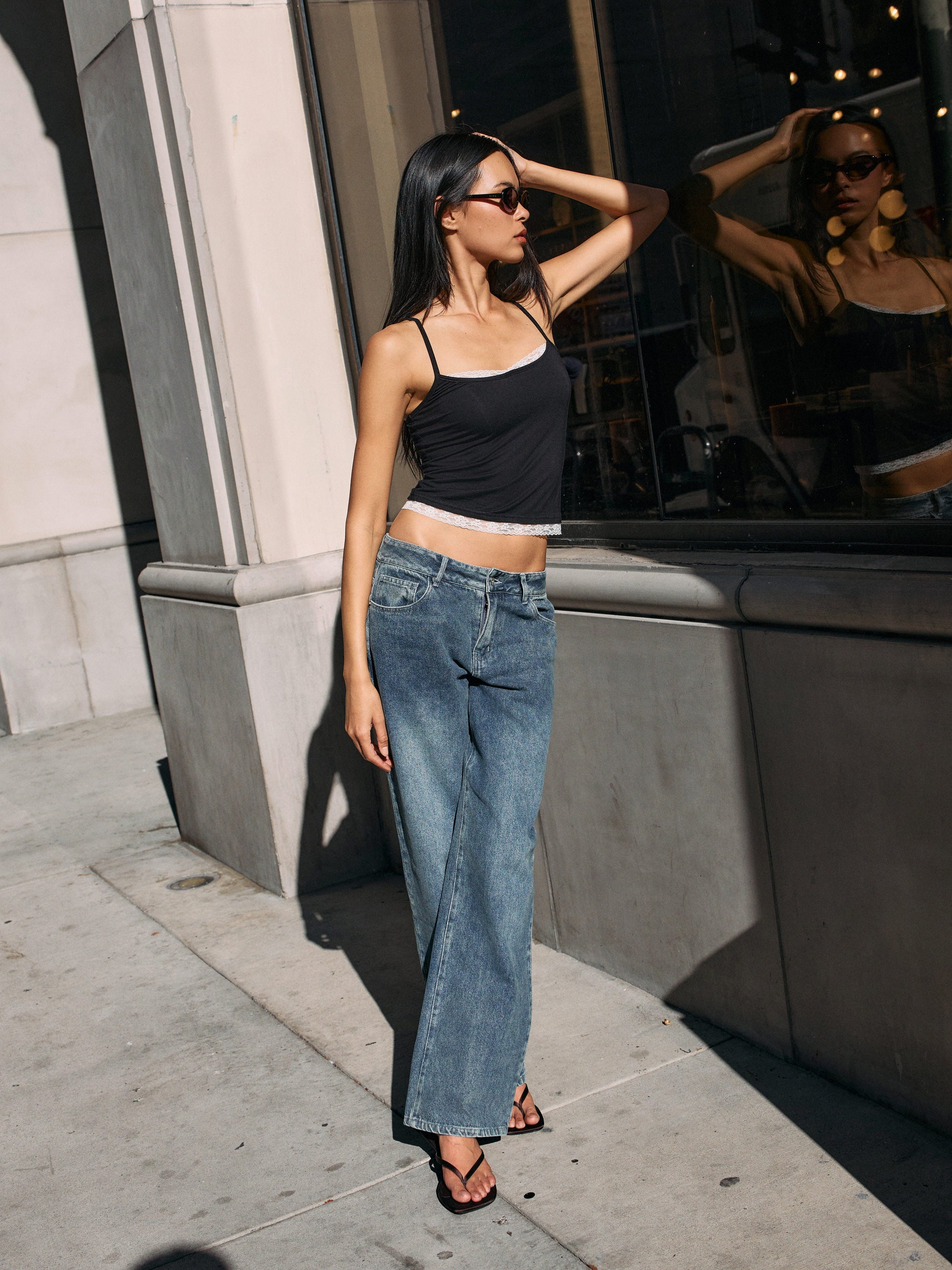 Model wearing BTTRMMT Drop Zone Low Rise Wide Leg Jeans in vintage blue, styled with a gray knit top while standing on a city street.