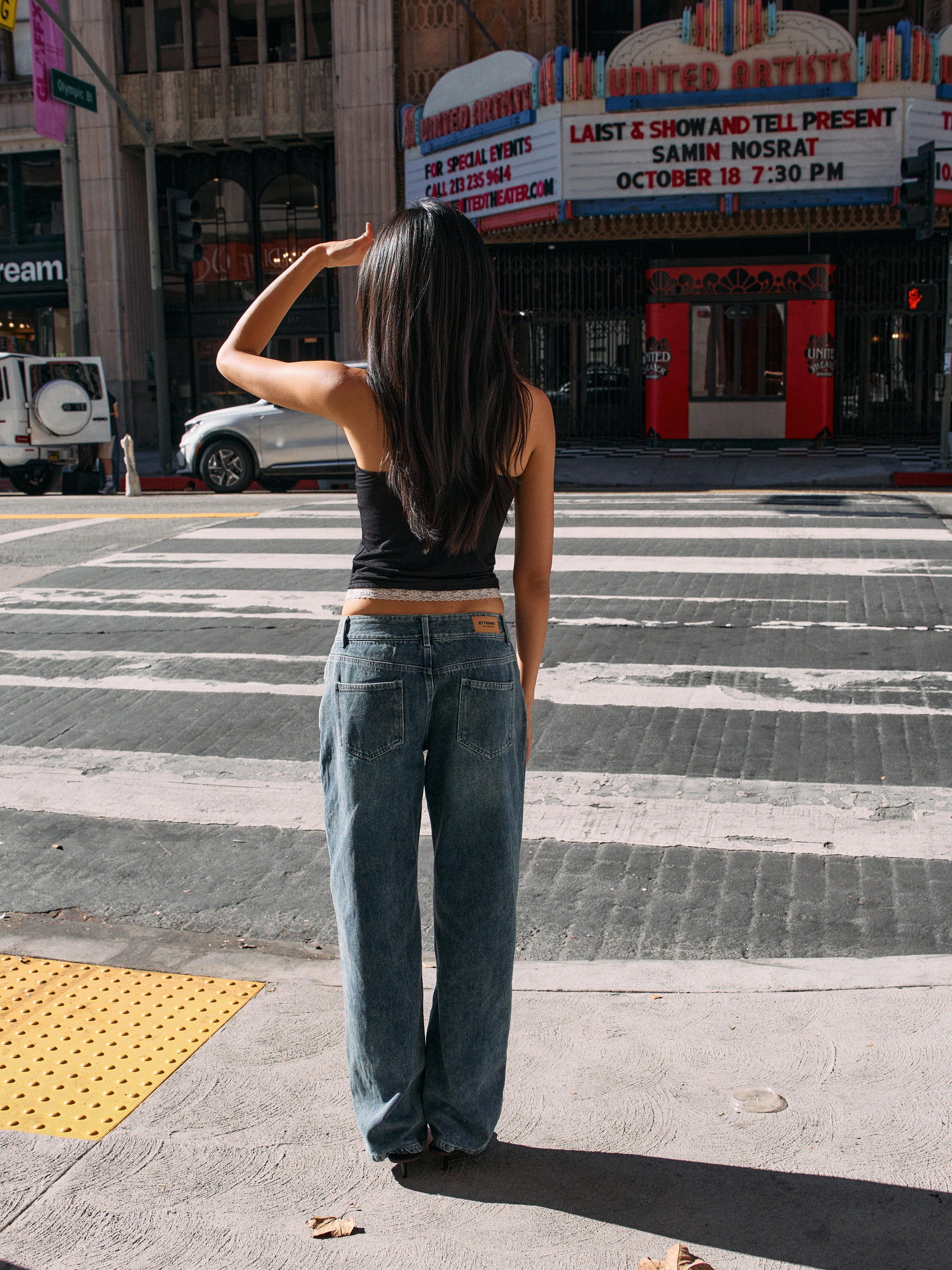 Model wearing BTTRMMT Drop Zone Low Rise Wide Leg Jeans in vintage blue, styled with a gray knit top while standing on a city street.