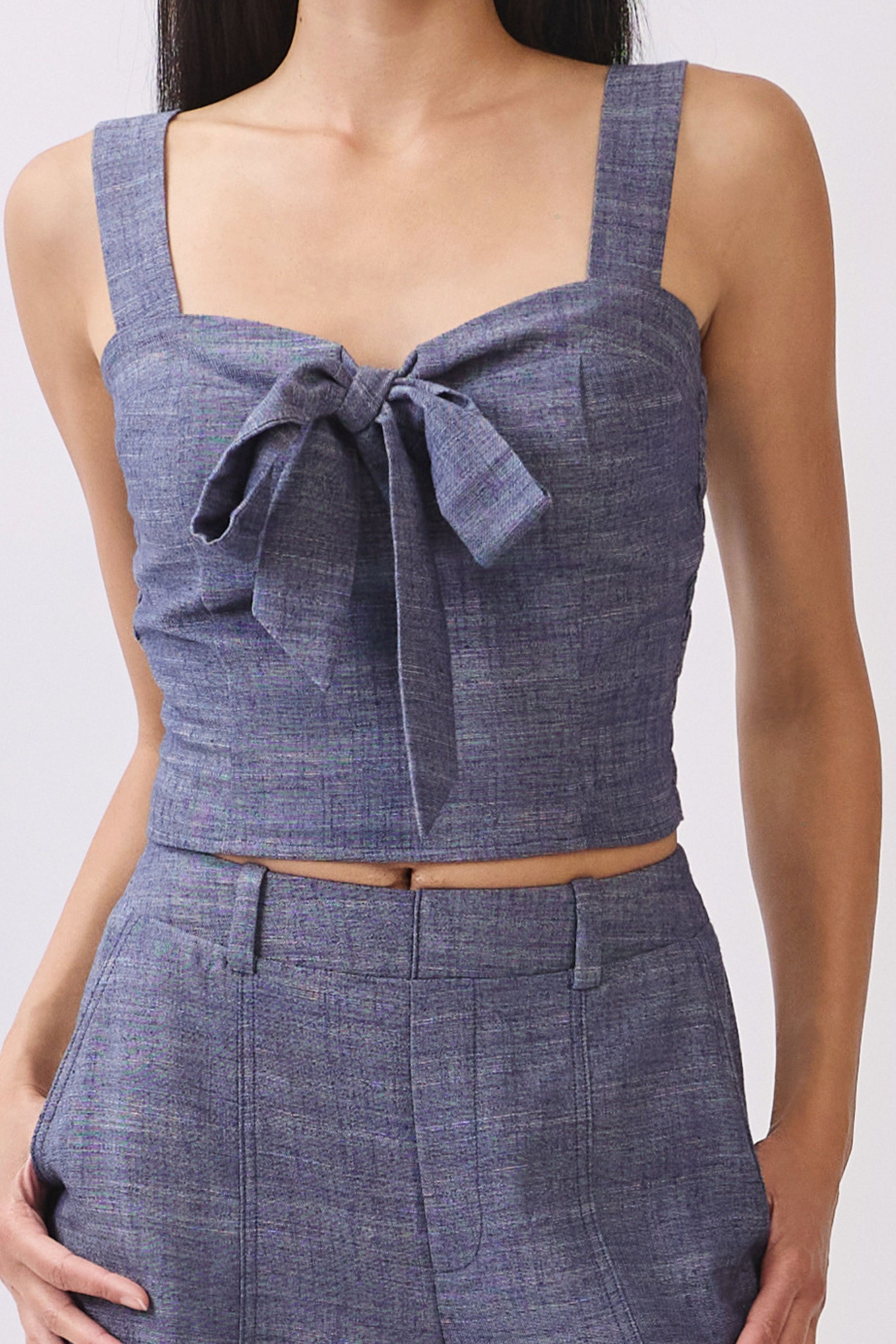 Close up of Model wearing BTTRMMT The Delilah Set, blue textured two-piece with tie-front crop top and matching wide-leg pants.