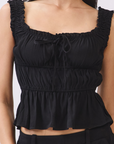 BTTRMMT black ruffle tank top close-up with smocked straps, tie front and peplum hem shown in detailed fabric view