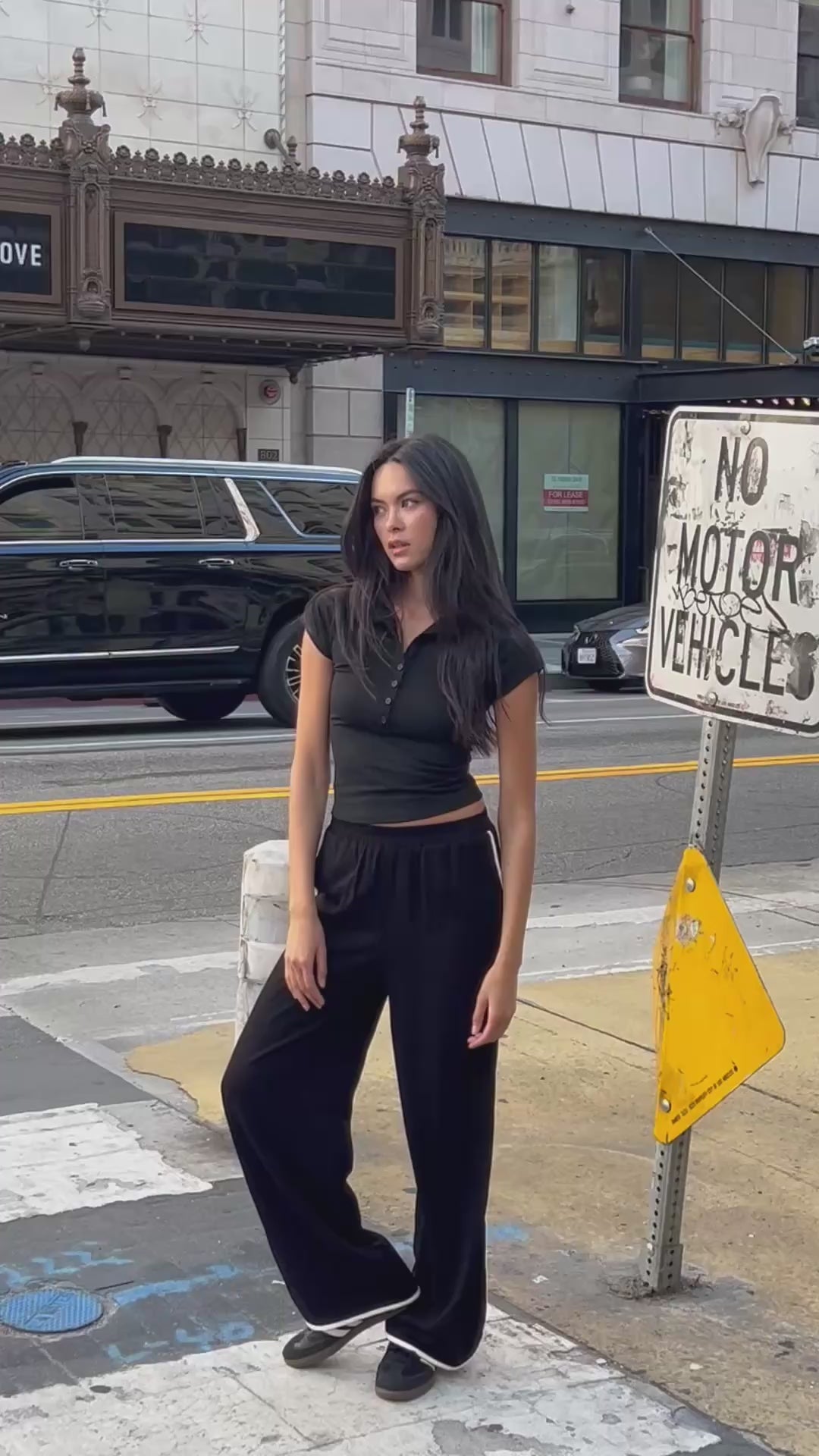Model posing in the Nova Contrast Trim Pants in black, styled with a fitted black polo top for a sleek streetwear look.